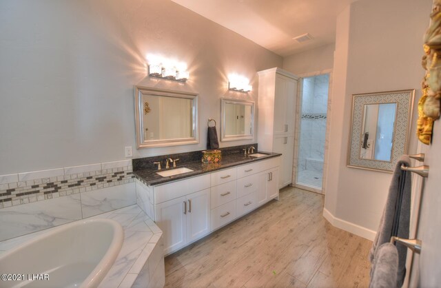 8551 River View Villas Dr Unit 15, Parker, AZ 85344 - full bathroom featuring a garden tub, double vanity, wood finished floors, tiled shower, and baseboards