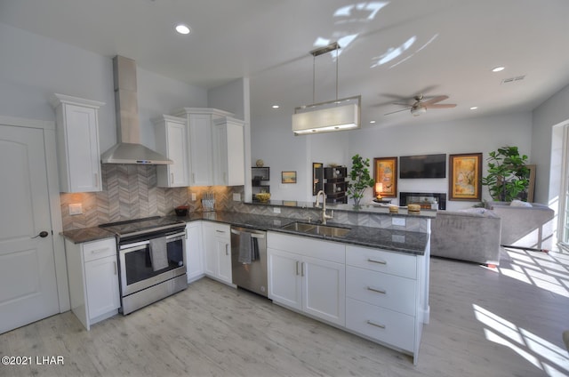 8551 River View Villas Dr Unit 15, Parker, AZ 85344 - kitchen featuring stainless steel appliances, wall chimney exhaust hood, a sink, a peninsula, and white cabinets