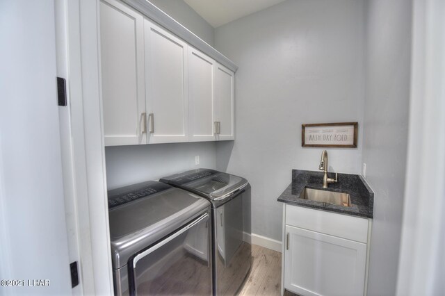 8551 River View Villas Dr Unit 15, Parker, AZ 85344 - washroom featuring cabinet space, washing machine and clothes dryer, light wood-style flooring, baseboards, and bar with sink