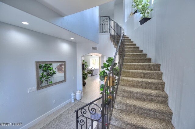 8551 River View Villas Dr Unit 15, Parker, AZ 85344 - stairs with arched walkways, recessed lighting, baseboards, wood finished floors, and a high ceiling