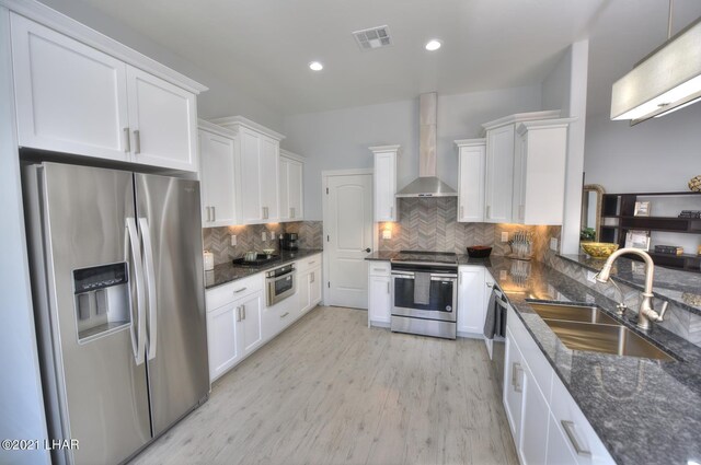 8551 River View Villas Dr Unit 15, Parker, AZ 85344 - kitchen with stainless steel appliances, a sink, wall chimney range hood, white cabinets, and tasteful backsplash