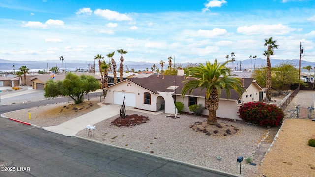 view of front of property with stucco siding, fence, a garage, a residential view, and driveway