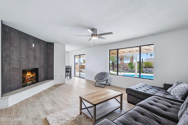 living area featuring light wood-type flooring, a fireplace, and a textured ceiling