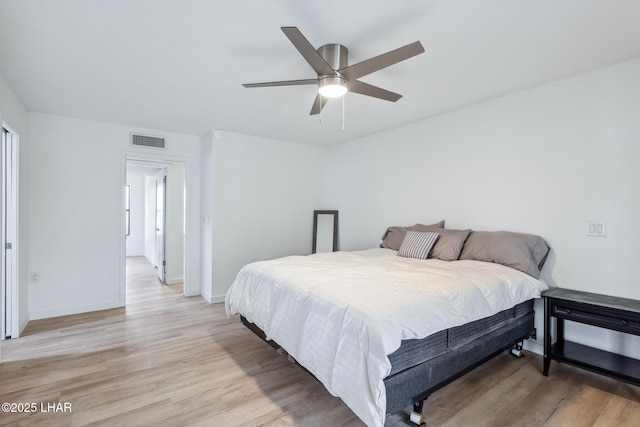 bedroom with a ceiling fan, light wood-type flooring, visible vents, and baseboards