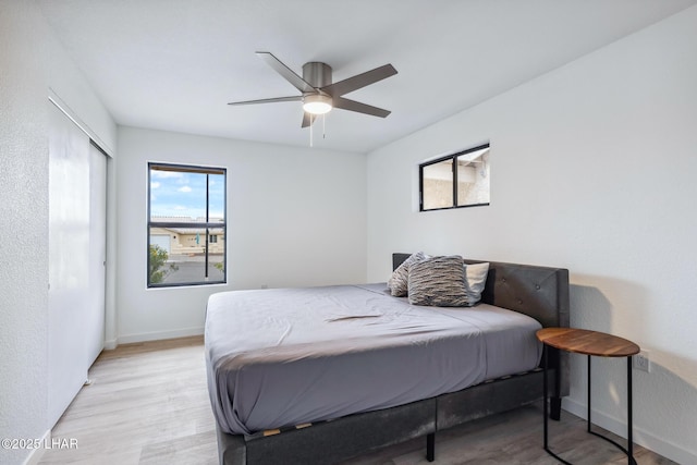 bedroom featuring a ceiling fan, light wood-style flooring, and baseboards