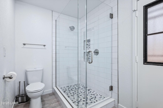 full bathroom with a wealth of natural light, a stall shower, wood finished floors, and toilet