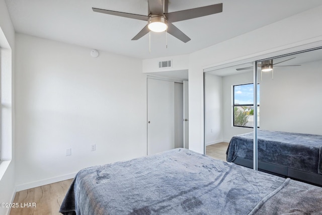 bedroom with light wood-style floors, baseboards, visible vents, and a ceiling fan