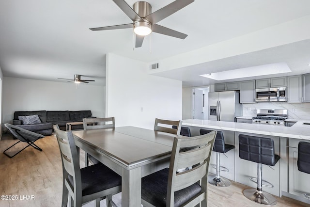 dining area featuring visible vents, ceiling fan, and light wood-style flooring