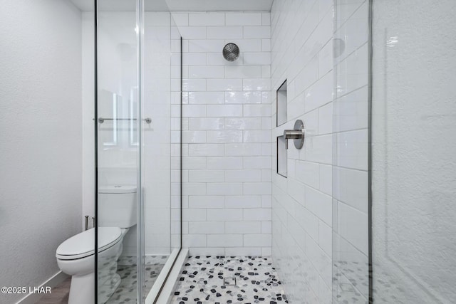 full bathroom featuring toilet, a stall shower, and a textured wall