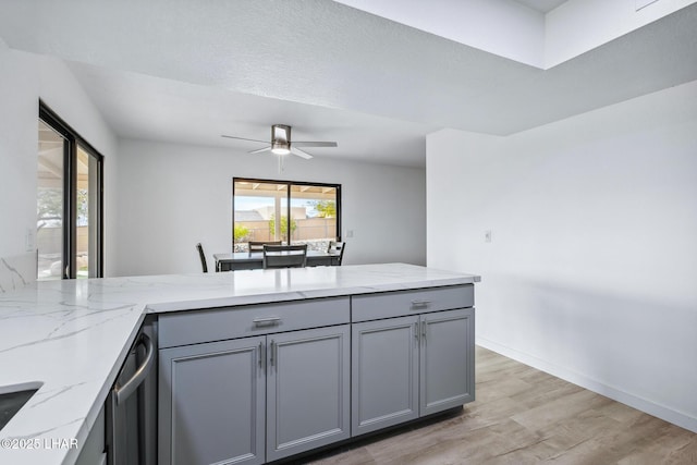 kitchen featuring light wood-style flooring, gray cabinetry, a peninsula, light stone countertops, and dishwasher