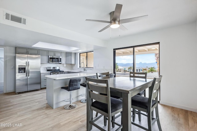 dining space featuring light wood-type flooring, baseboards, visible vents, and a mountain view