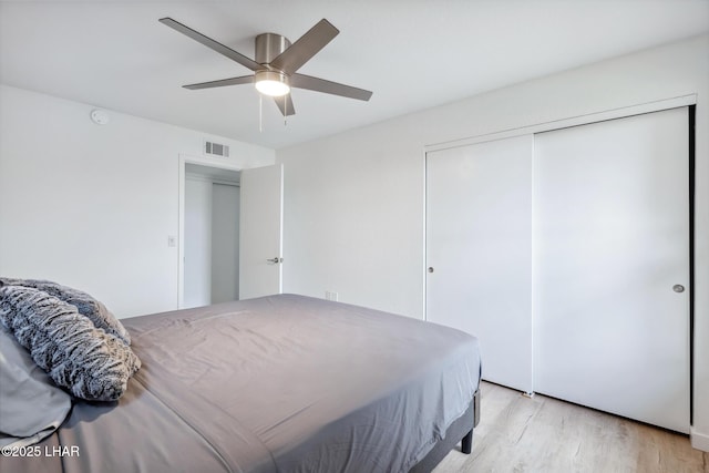 bedroom featuring light wood finished floors, a ceiling fan, visible vents, and a closet