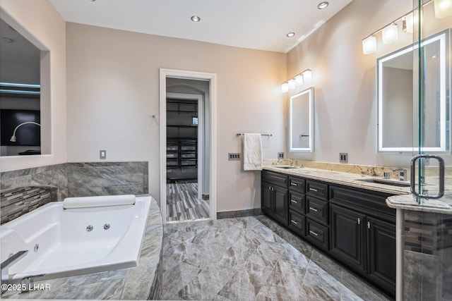 bathroom with a sink, baseboards, a jetted tub, and double vanity