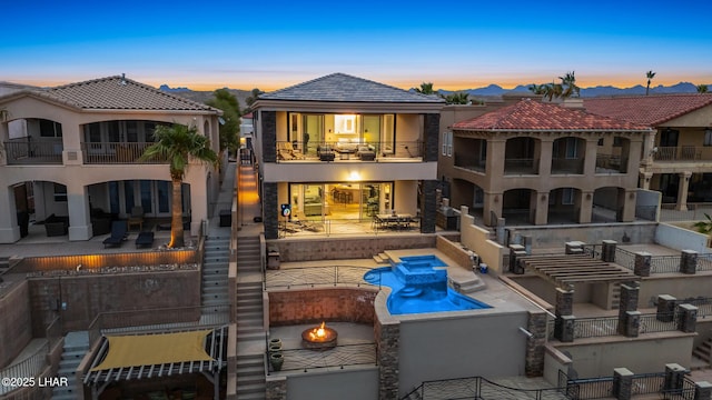 rear view of house featuring a balcony, a patio area, a pool with connected hot tub, and stucco siding