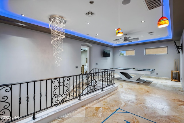 game room with visible vents, a raised ceiling, arched walkways, and ceiling fan with notable chandelier