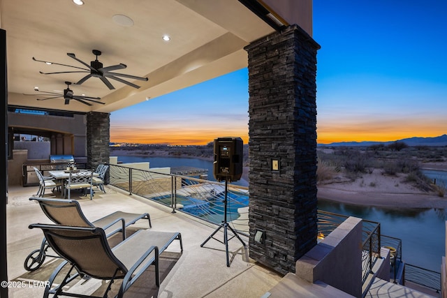 view of patio / terrace featuring outdoor dining area, a ceiling fan, and a water and mountain view