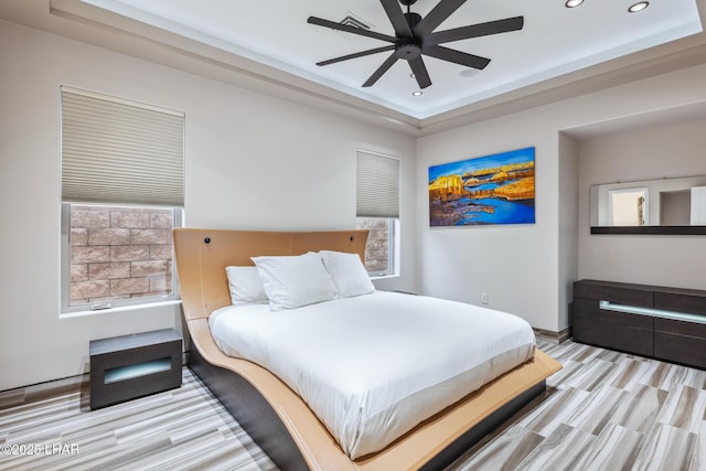 bedroom with a raised ceiling, multiple windows, recessed lighting, and ceiling fan