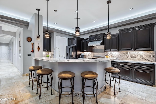 kitchen with visible vents, stainless steel fridge with ice dispenser, arched walkways, under cabinet range hood, and a kitchen breakfast bar