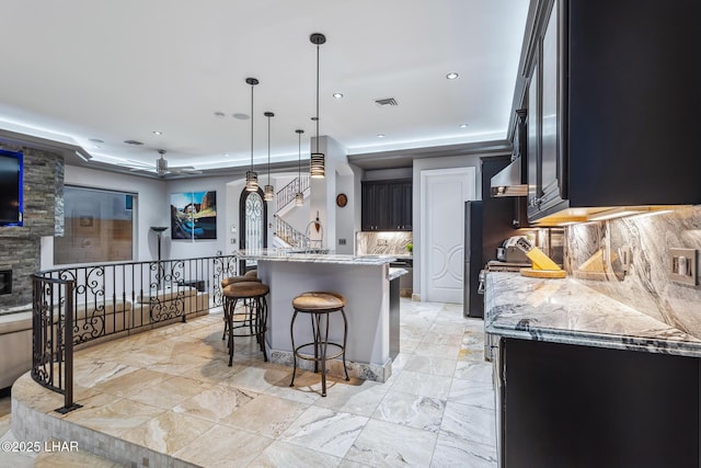 kitchen featuring visible vents, decorative light fixtures, a kitchen breakfast bar, decorative backsplash, and a raised ceiling