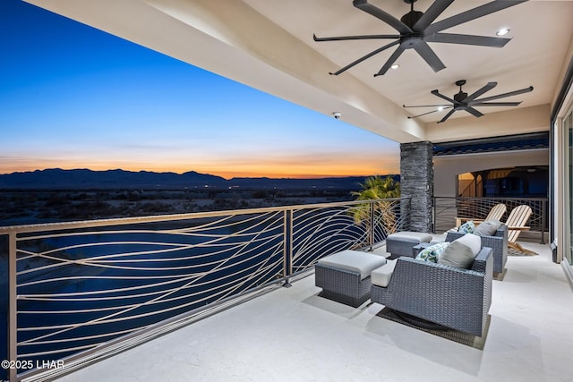 patio terrace at dusk with a balcony, a mountain view, and ceiling fan