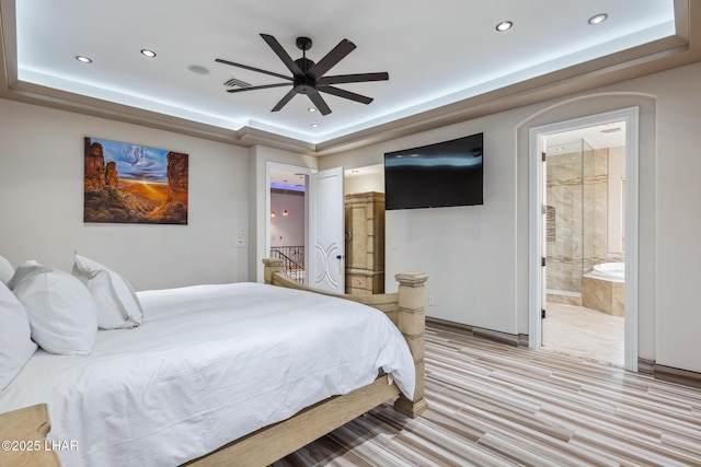 bedroom with a tray ceiling, recessed lighting, visible vents, and ensuite bathroom