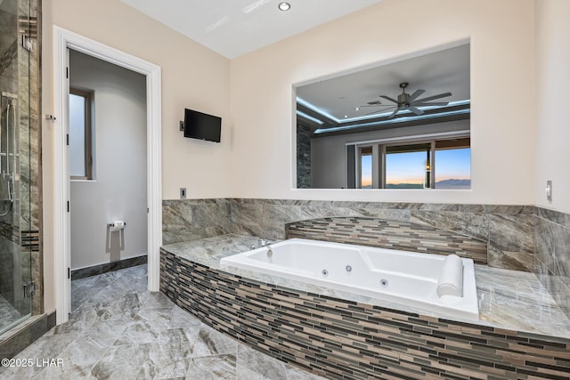 full bathroom with marble finish floor, a ceiling fan, a jetted tub, a shower stall, and a raised ceiling