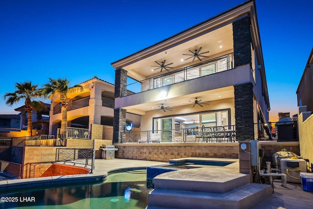 rear view of house with ceiling fan, a patio, a balcony, an outdoor pool, and an in ground hot tub