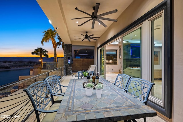 view of patio with ceiling fan, a water view, outdoor dining space, and fence