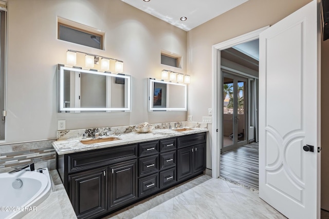 full bathroom with double vanity, a bath, and a sink