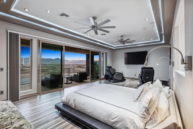 bedroom with a raised ceiling, recessed lighting, access to exterior, and visible vents