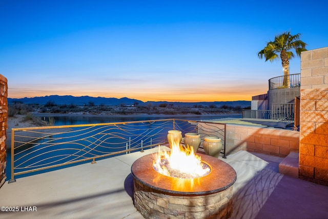 patio terrace at dusk featuring a fire pit and a mountain view