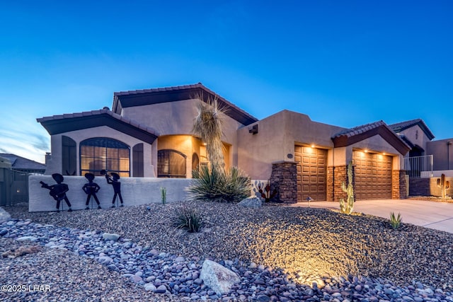 view of front of house with stucco siding, stone siding, fence, concrete driveway, and an attached garage