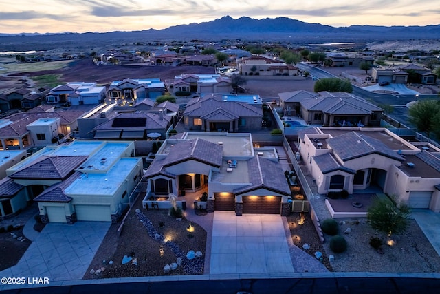 aerial view at dusk featuring a mountain view and a residential view