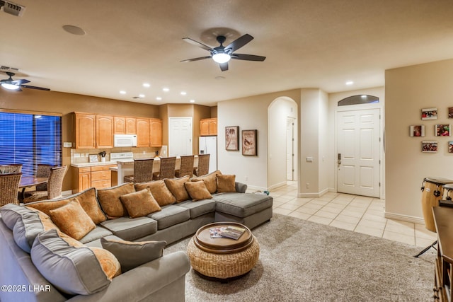 living room with light tile patterned floors, visible vents, recessed lighting, arched walkways, and ceiling fan