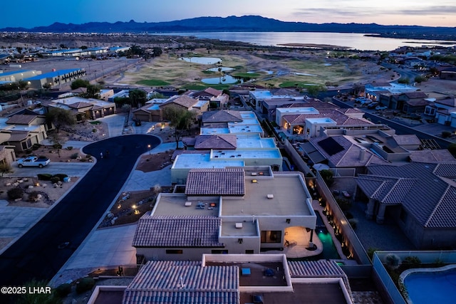 aerial view at dusk featuring a water and mountain view