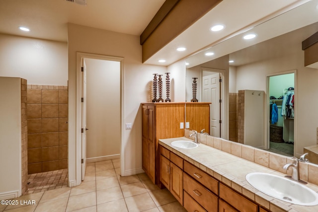 full bathroom featuring double vanity, a spacious closet, recessed lighting, and a sink