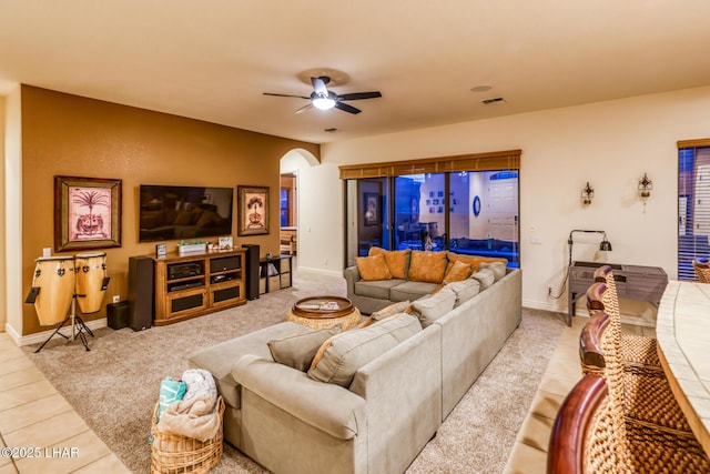 living area with visible vents, a ceiling fan, arched walkways, and baseboards