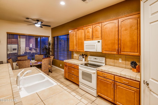 kitchen with ceiling fan, tile countertops, decorative backsplash, white appliances, and a sink