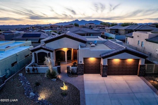 view of front facade with stucco siding, concrete driveway, a garage, a tiled roof, and a mountain view