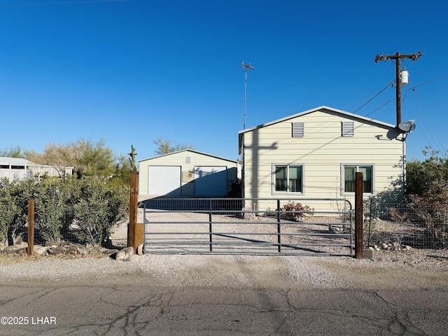 view of front of house with an outbuilding, a gate, and fence