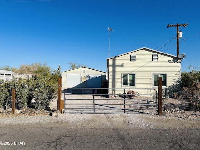 view of front facade featuring a gate, a detached garage, fence, and an outdoor structure