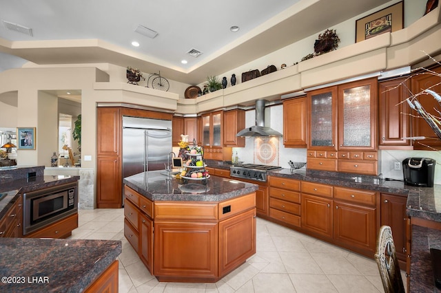 8480 Miraleste Shores Dr, Parker, AZ 85344 - kitchen featuring wall chimney range hood, built in appliances, light tile patterned floors, brown cabinetry, and recessed lighting