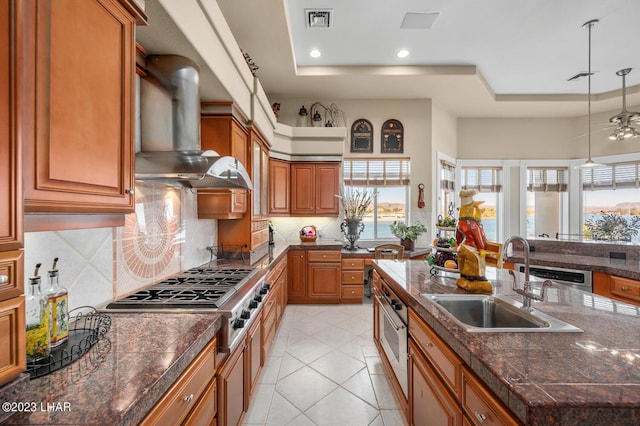 8480 Miraleste Shores Dr, Parker, AZ 85344 - kitchen with wall chimney exhaust hood, a tray ceiling, appliances with stainless steel finishes, brown cabinets, and recessed lighting