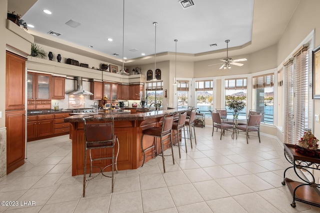 8480 Miraleste Shores Dr, Parker, AZ 85344 - kitchen with wall chimney exhaust hood, brown cabinetry, light tile patterned floors, a breakfast bar, and recessed lighting