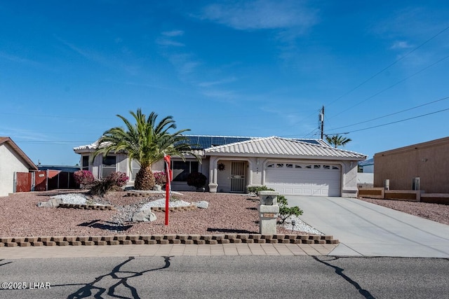 single story home with a garage, concrete driveway, a tiled roof, roof mounted solar panels, and stucco siding