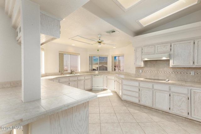 kitchen with sink, light tile patterned floors, white dishwasher, kitchen peninsula, and black electric stovetop