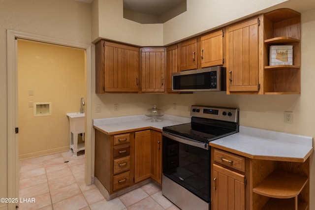 kitchen featuring open shelves, stainless steel appliances, brown cabinetry, and light countertops