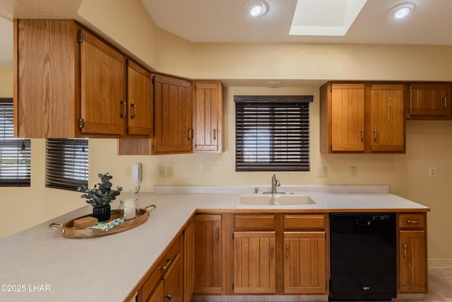 kitchen featuring a sink, a skylight, brown cabinetry, light countertops, and dishwasher