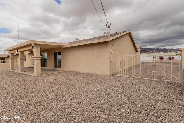 rear view of property with a patio area, stucco siding, and fence