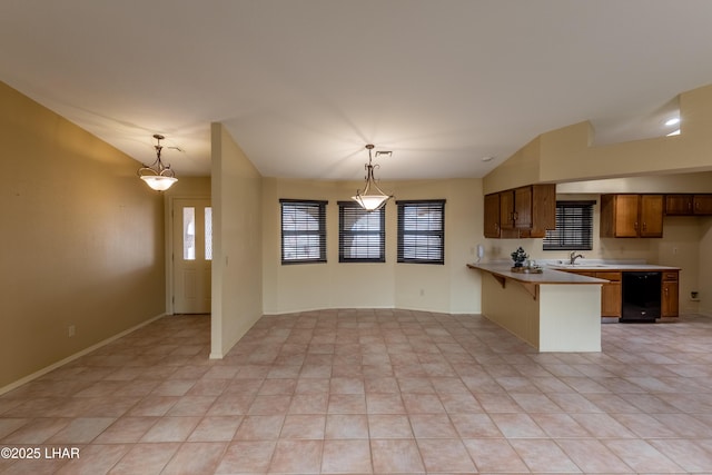 kitchen featuring brown cabinets, a peninsula, light countertops, vaulted ceiling, and hanging light fixtures